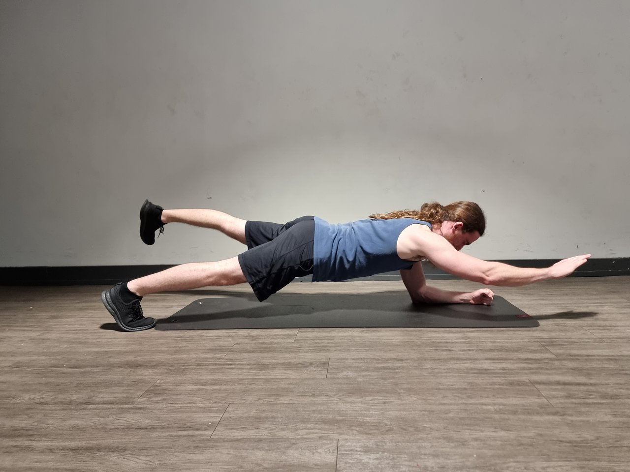 A man performing a plank core exercise with opposite arm and leg raised