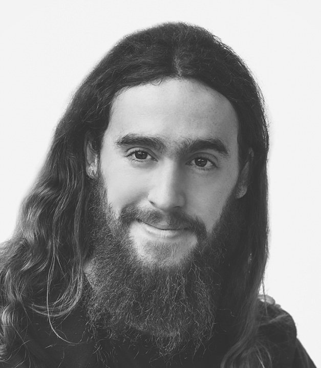 A greyscale portrait photo of a smiling man with long hair and beard